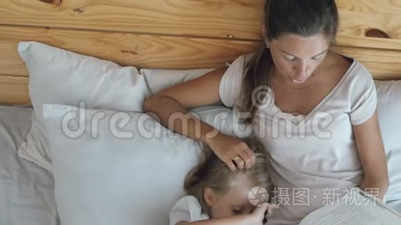 妈妈带着女儿在床上看书