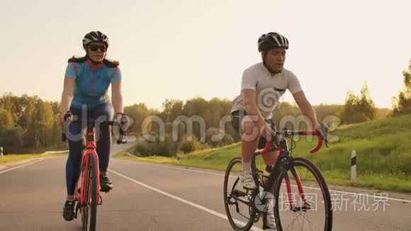 一对骑自行车的夫妇在日落时分骑着自行车走在公路上，在高处玩耍