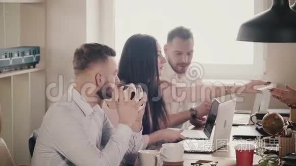 快乐年轻的欧洲商人坐在桌子旁，与笔记本电脑一起工作在现代健康的办公室，慢动作。