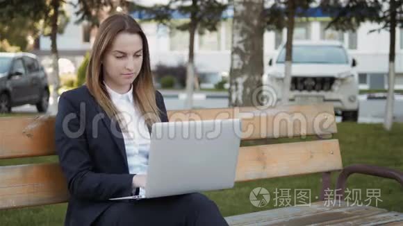 年轻漂亮的商务女性使用笔记本电脑坐在户外