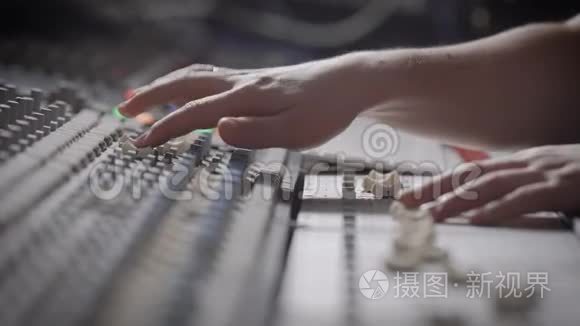 侧视镜头的音乐家工作的音频混合控制台在音乐工作室。