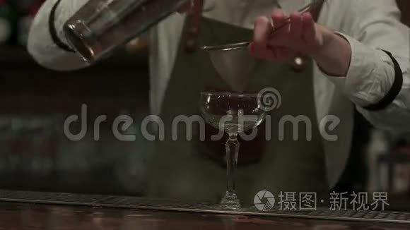 专家酒吧老板把准备好的摇床鸡尾酒倒入玻璃杯中，然后把它放在夜总会的餐巾上