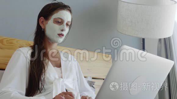 带面罩的女人用笔记本电脑视频