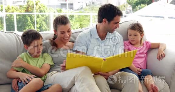 可爱的一家人一起躺在沙发上看相册
