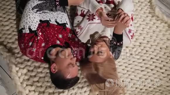 幸福的年轻夫妇躺在家里的地板上。 圣诞节庆典。 上景。