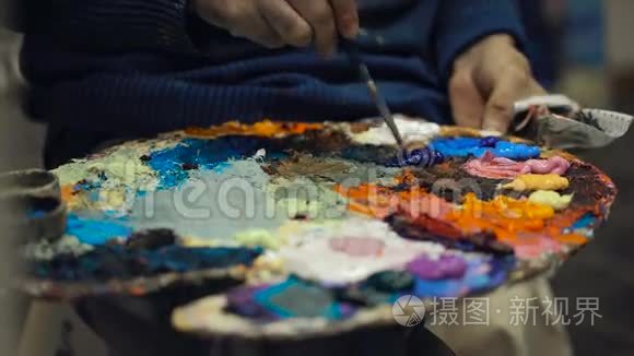 艺术家将各种颜色的油画颜料混合在托盘上