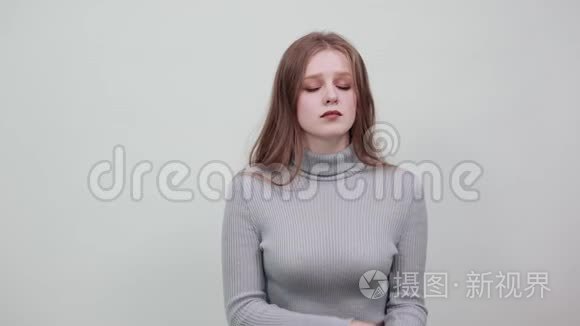 一位身穿灰色毛衣的年轻红发女子轻轻地闭上了眼睛