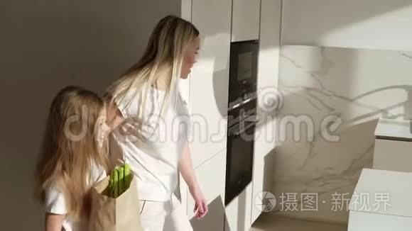 金发白种人的母亲带着女儿上厨房来购物从健康的有机食品中取出大棕色纸袋