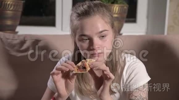 年轻可爱的女人坐在客厅沙发上，看电视，吃披萨。 特写