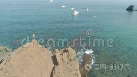 空中射击一名男子站在透明的海面上的悬崖上