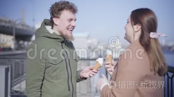 快乐的年轻女人用冰淇淋抚摸男人`鼻子，笑着。 积极的高加索夫妇约会的肖像