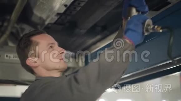 近距离侧面观察自信的白人男子在工作服使用专业设备的汽车维修。 年轻男性