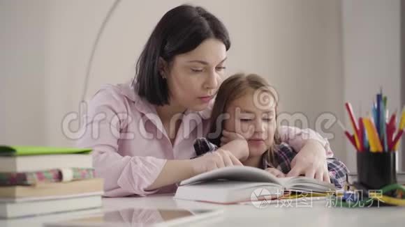 聪明的白种人女孩为妈妈读书的肖像。 可爱的学童和母亲一起做作业。 家长帮助