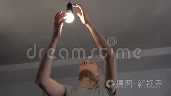 在一个黑暗的房间里，一个女人用一盏新的LED了一盏节能灯..
