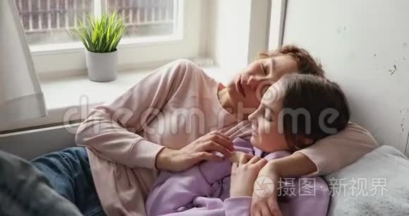 快乐的妈妈拥抱着十几岁的女儿，说着轻松的躺在床上