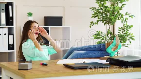 一个漂亮的办公室女孩，在工作休息的时候，脚在桌子上休息，打电话