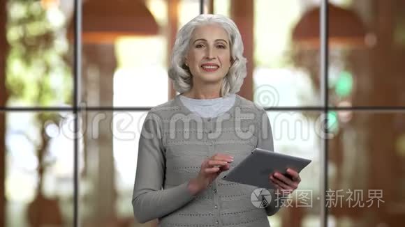 积极有吸引力的老太太拿着平板电脑说话。