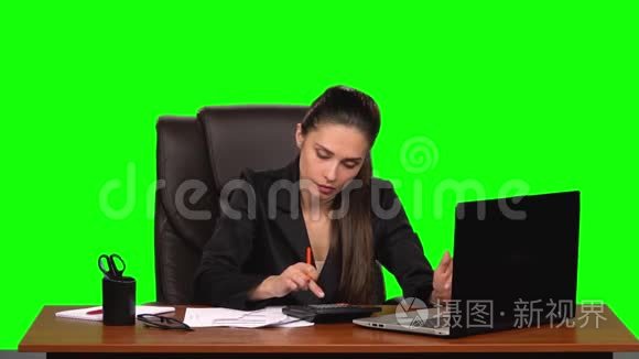 商务女性在笔记本电脑上工作，将数据与计算器上的计数进行比较，并在文档中输入。 绿色