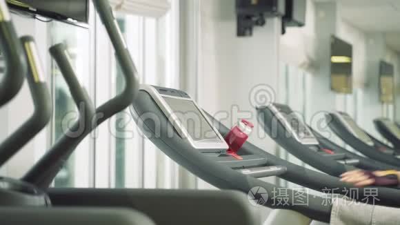 年轻的健身妇女开始有氧运动，在健身房的跑步机上行走。