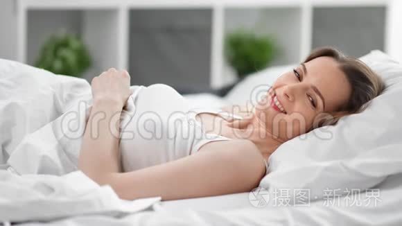 迷人的年轻女性躺在舒适的床上享受早晨。4k龙红色摄像机