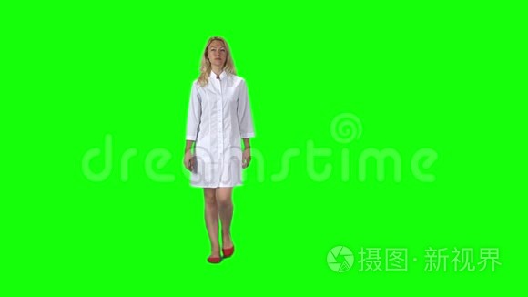 一个金发女孩，穿着白色的医疗外套，对着绿色的屏幕。慢动作