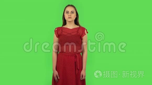 穿着红色衣服的温柔女孩被吓坏了，然后宽慰地叹息，微笑着。 绿色屏幕