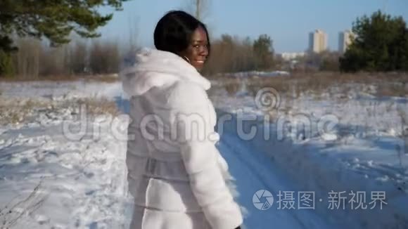 快乐的黑人妇女走在冬天森林的雪道上