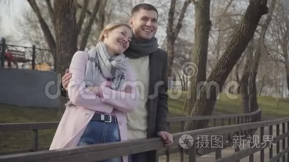 笑着的年轻人拥抱公园里年长的快乐女人。 快乐的白人夫妇的肖像与年龄差异