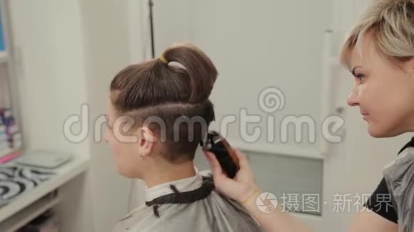 专业的理发师女士用剪发器剪发给客户。