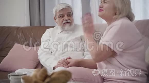开朗的高加索老人和成熟的女人在家里谈笑风生的肖像。 快乐的退休夫妇