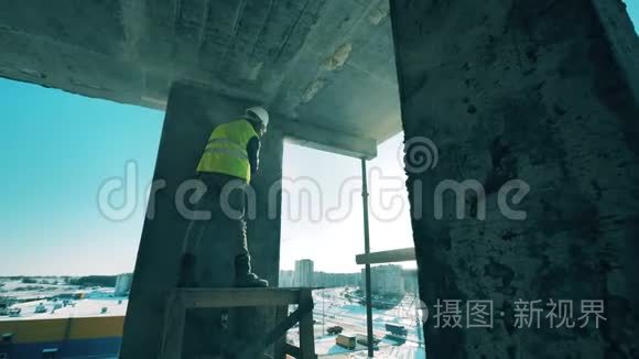 一个人在建筑工地上用混凝土墙工作。