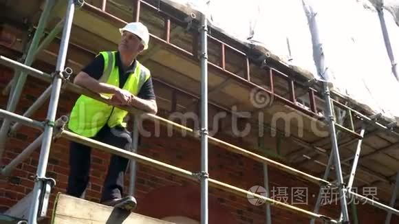 建筑工地站在脚手架上的男建筑工头、工人、测量员或建筑师