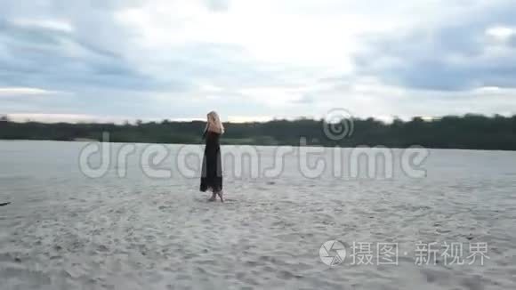 沙滩上穿着黑色裙子的金发女人视频