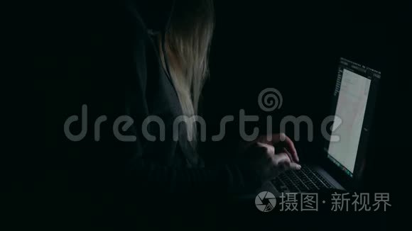 头罩里的黑客在暗室里用笔记本电脑打字。
