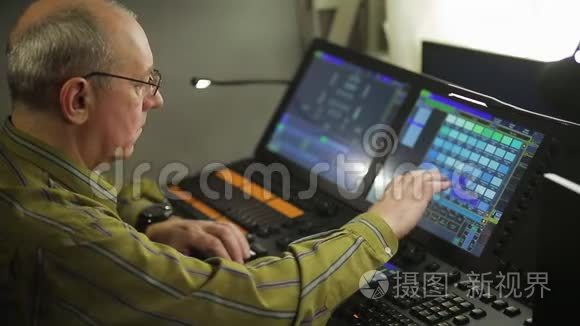 一个男性照明程序员在遥控器编程舞台灯光为一个节目。