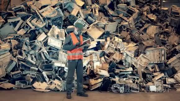 有一堆有缺陷的设备在垃圾场的男工。 垃圾，塑料回收厂..