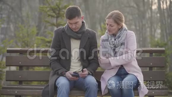 在智能手机上看了他的留言后，一位成年白种人女人离开了悲伤的年轻人肖像。 丈夫或丈夫