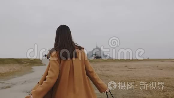 镜头跟随美丽优雅的女人步行到著名的蒙特圣米歇尔岛城堡阴天慢动作。