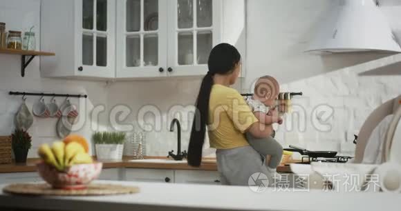 年轻的妈妈抱着孩子做家务视频