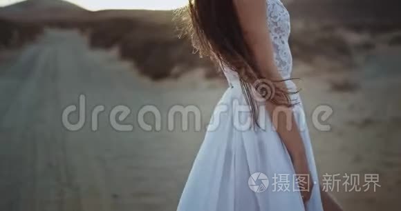 美丽的女士，留着长发，穿着婚纱，在夕阳下美丽的景色中享受着时光