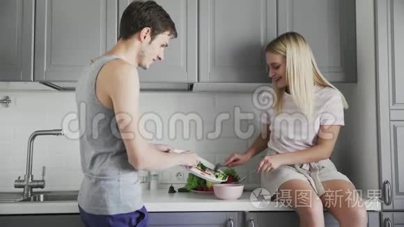 年轻人和女孩坐在桌子上，一起切蔬菜做沙拉，在厨房吃午饭