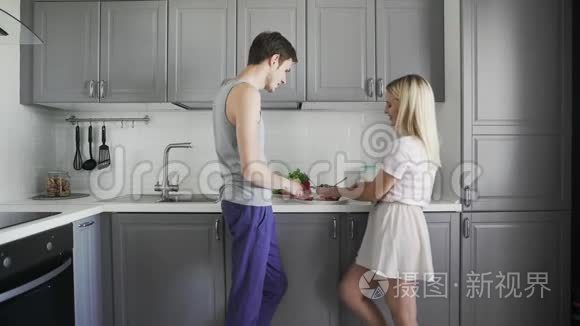 爱的夫妻在厨房里聊天，切西红柿，一起准备沙拉