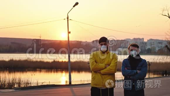 新的Covid19概念两个朋友带着防护面罩站在公园中央的摄像头前
