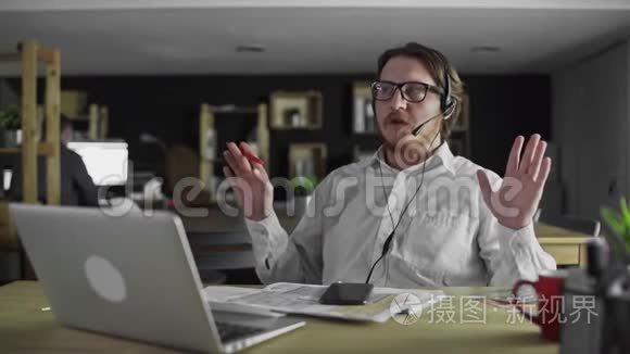 戴耳机的年轻经理正在办公室用笔记本电脑工作