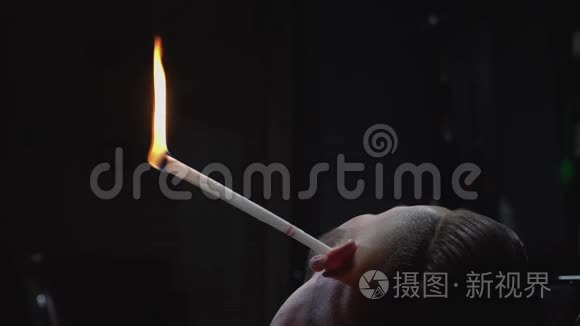 时髦的男人用燃烧的火焰从耳朵里回发