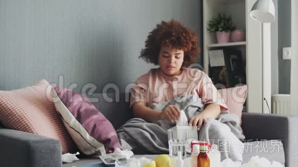 生病的非裔美国女孩在家里沙发上患流感病毒。 她用湿巾打喷嚏