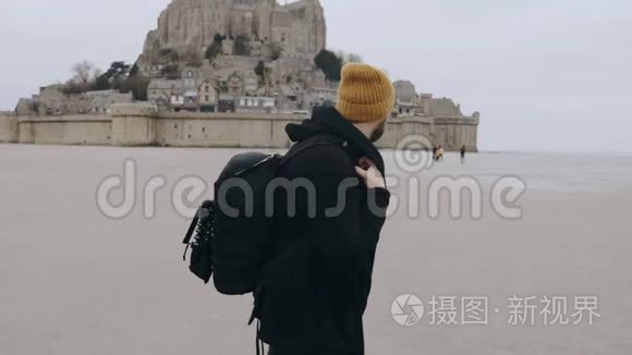 快乐兴奋的欧洲游客背着背包离开史诗般的诺曼底圣米歇尔城堡