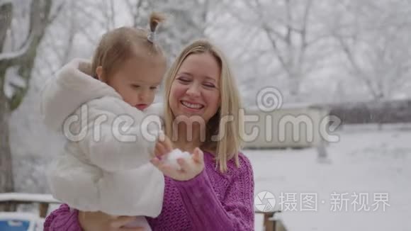 年轻的金发女郎带着可爱的女婴在雪地公园里玩