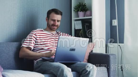 快乐微笑的年轻人在家看电脑和工作。