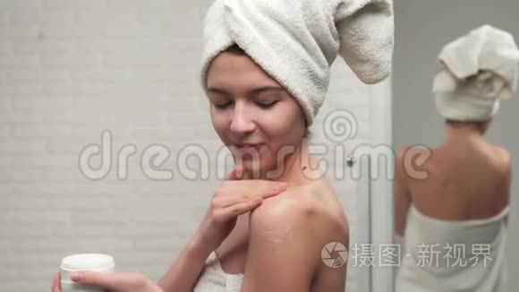 女人拿毛巾把奶油放在肩膀上。